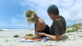Vacationers look on with disapproval as a milf with her BF films anal content right on the beach