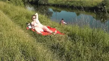 MILF sexy Frina on river bank undressed and sunbathes naked. Random man fisherman watching for her, and in the end decided to join naked woman. Wild beach. Nudist beach. Public nudity. Public exposure. Naked in public