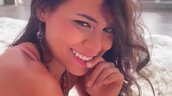 Красивая девушка в розовом платье и красных туфлях позирует голой